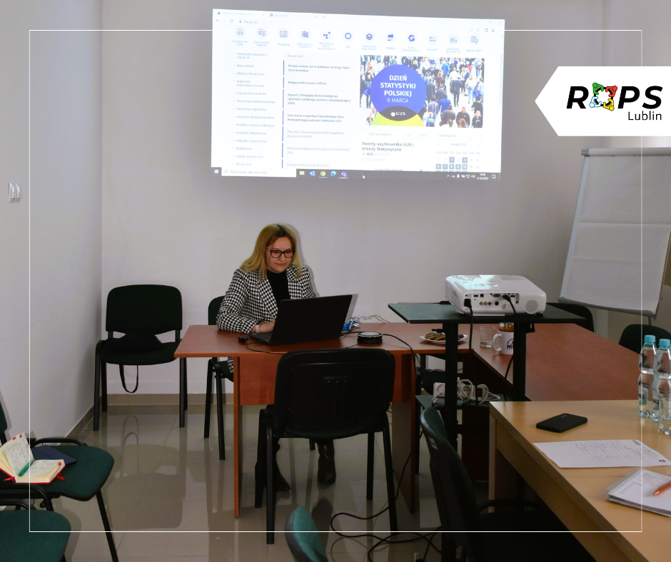 Pracownik ROPS - Pani Monika Kądziela - włącza prezentację multimedialną na komputerze. Za nią na rzutniku wyświetla się obraz.