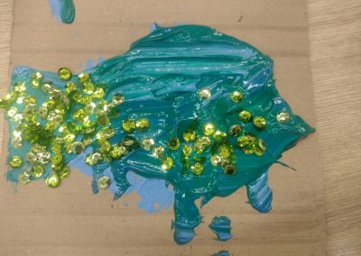 Zdjęcie niebieskiej ryby malowanej farbami ze złotymi łuskami z cekinów