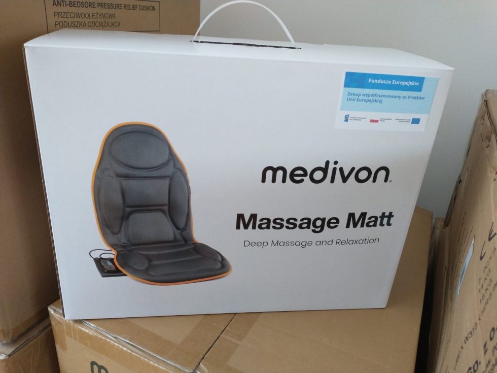 Pudełko z produktem o nazwie „medivon Massage Matt”, przedstawiające czarną matę masującą z pomarańczowym obramowaniem. W prawym górnym rogu umieszczono niebieską naklejkę z informacją o współfinansowaniu zakupu ze środków Unii Europejskiej oraz logotypami unijnymi.