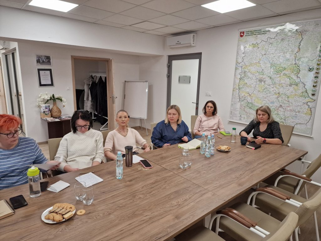 Uczestnicy szkolenia siedzą przy stołach i słuchają prowadzącego szkolenie.