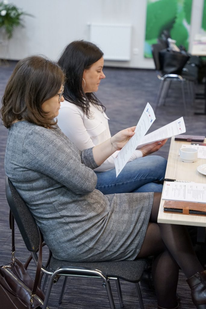 kobiety patrzą w kartki z notatkami, siedzą na krzesłach