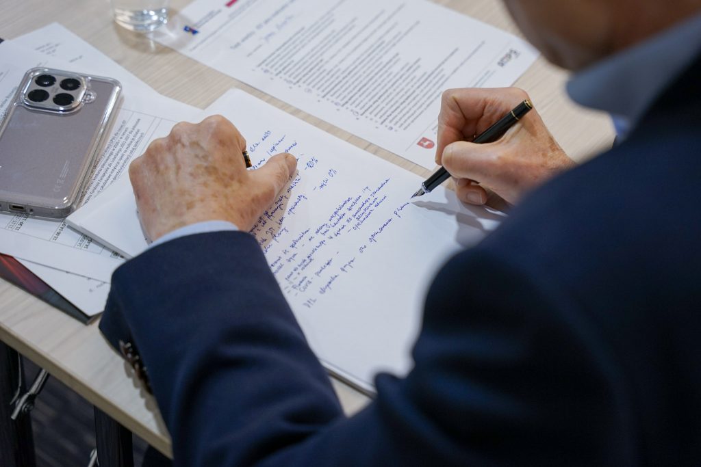 mężczyzna notuje w zeszycie. pisze piórem, obok leży telefon