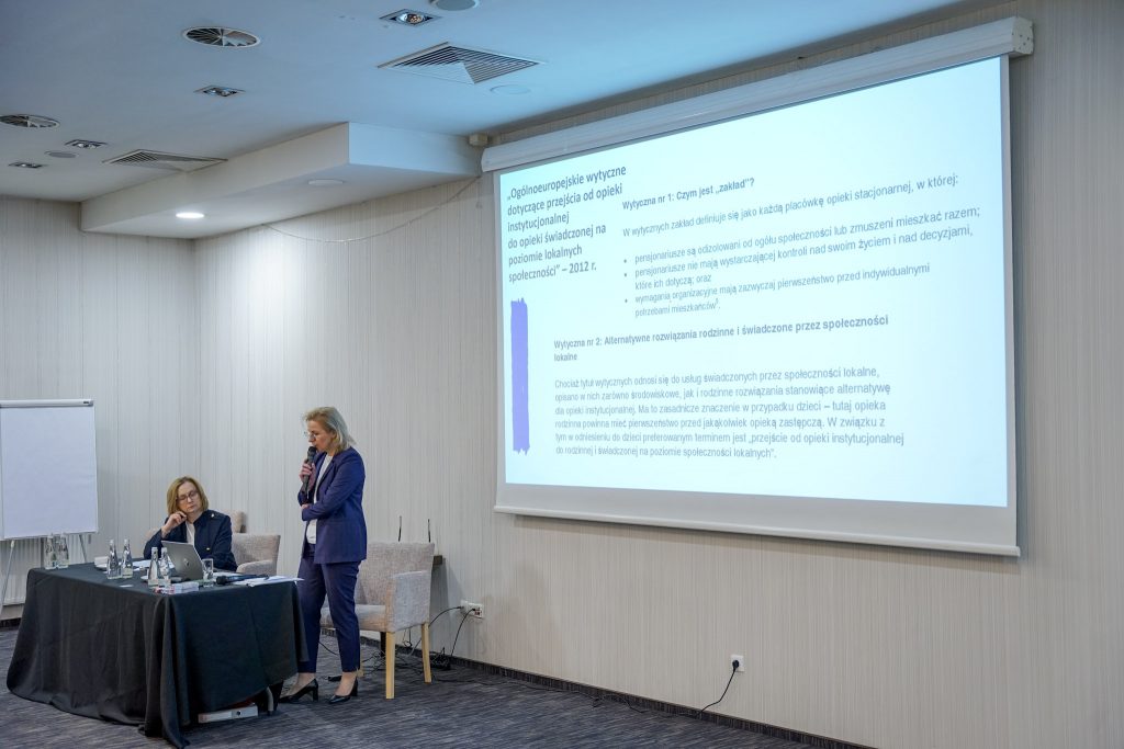 kobieta prowadzi wykład. w tle slajdi. obok siedzi druga kobieta